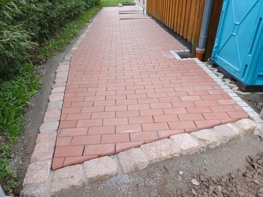 Gehweg mit roten Betonsteinpflaster gepflastert und mit Natursteineinfassung – Galabau Schurig Klipphausen